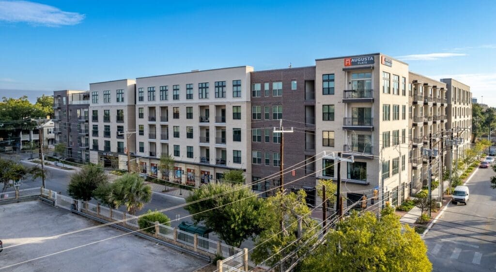 Aerial view of Augusta Flats, a modern residential apartment complex in San Antonio, Texas, showcasing its urban architecture and street layout